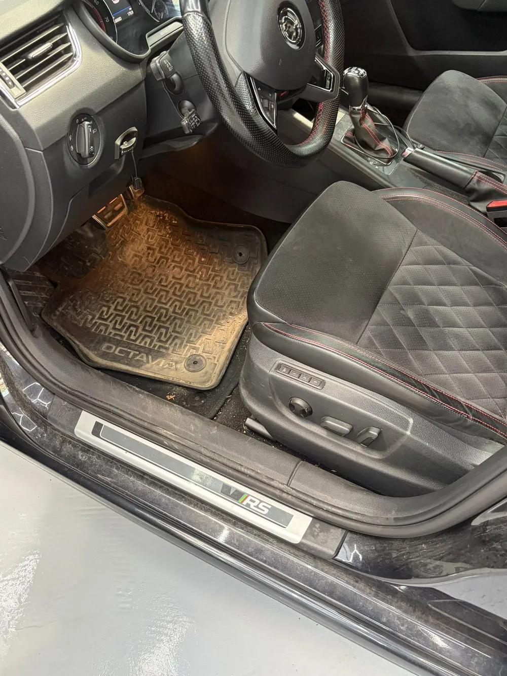 Škoda Octavia RS pred čistením — zablatené gumené koberce a znečistený priestor vodiča pri odovzdaní do štúdia